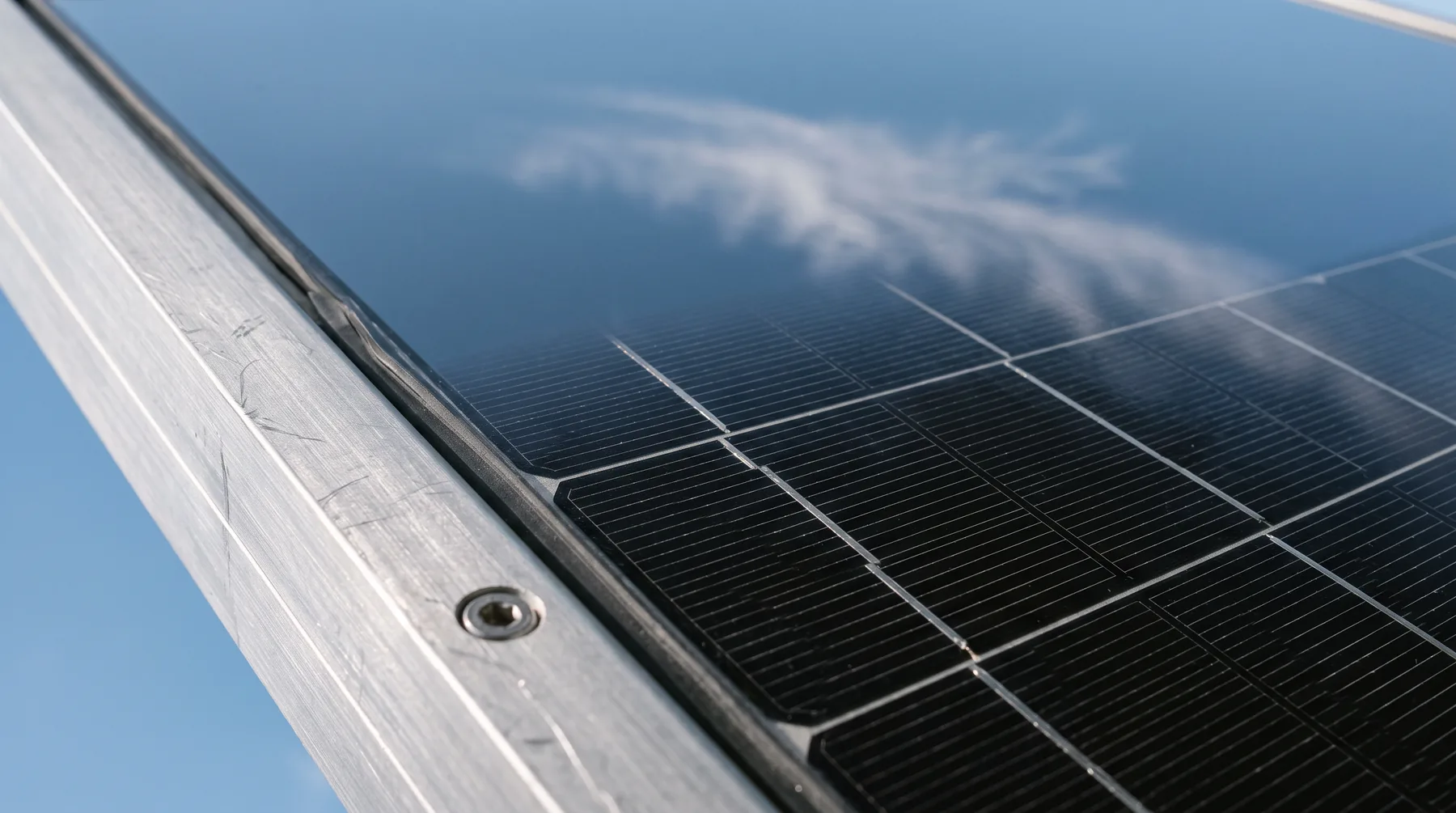 Close-up of solar panel glass reflecting a blue sky